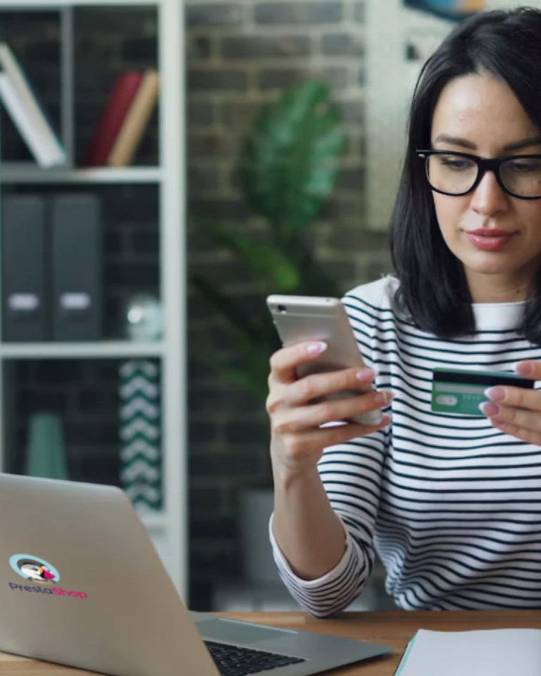 Tiendas online PrestaShop en Barcelona: compra con el móvil y tarjeta junto a un portátil con el logotipo de PrestaShop